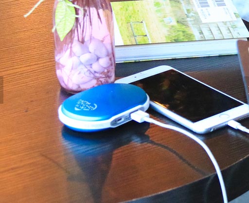 A battery operated hand warmer charging a smartphone